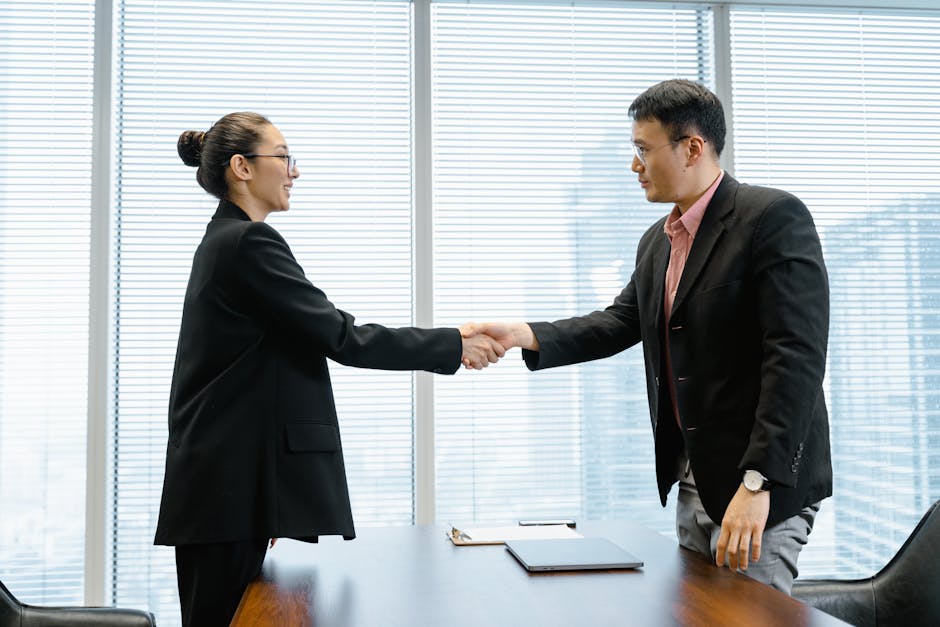 Two business professionals exchange a handshake in a modern office, sealing a deal.